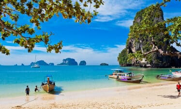 Eau turquoise, plage de sable fin encadreés par des végétations luxuriantes en Thaïlande.