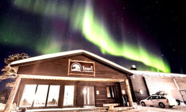 Magnifique aurore boréale au dessus d'une maison à l'architecture typique.