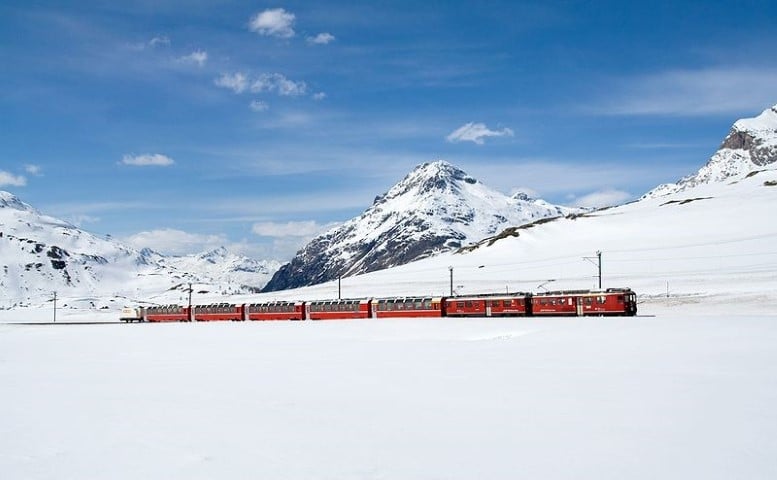 Paysage de montagne enneigée d'un blanc immaculé, ponctuée par le train en Suisse