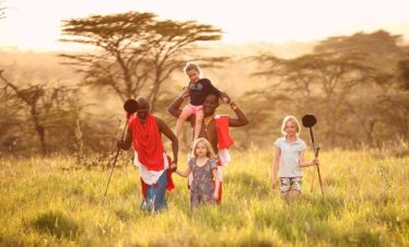 Plusieurs enfants se promenant dans la savane avec un guide dans un très beau paysage.