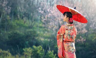 Jolie et jeune japonaise en tenue traditionnelle portant une ombrelle dans un cadre verdoyant