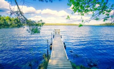 Paysage de carte postale avec un pont en bois sur un magnifique lac dans un cadre de verdure