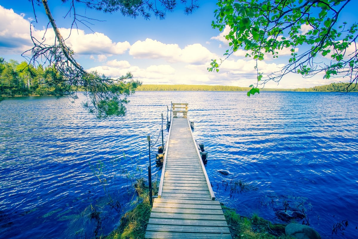 Paysage de carte postale avec un pont en bois sur un magnifique lac dans un cadre de verdure