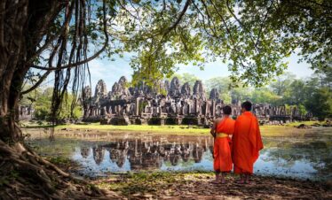 deux moines dans un cadre de verdure avec un temple au fond