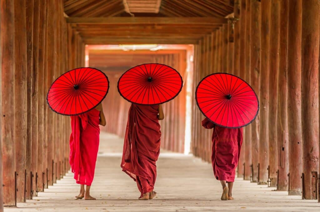 Trois moines vue de dos, abrités par des parapluies