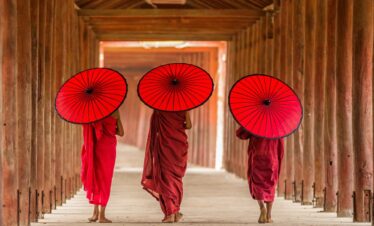 Trois moines vue de dos, abrités par des parapluies